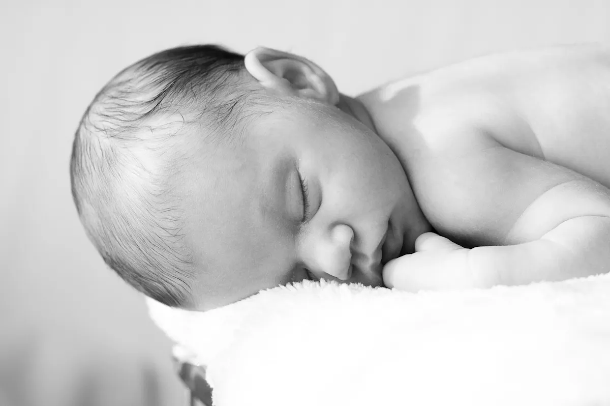 schlafendes Baby auf weißer Decke fotografiert von Valerija Ecker