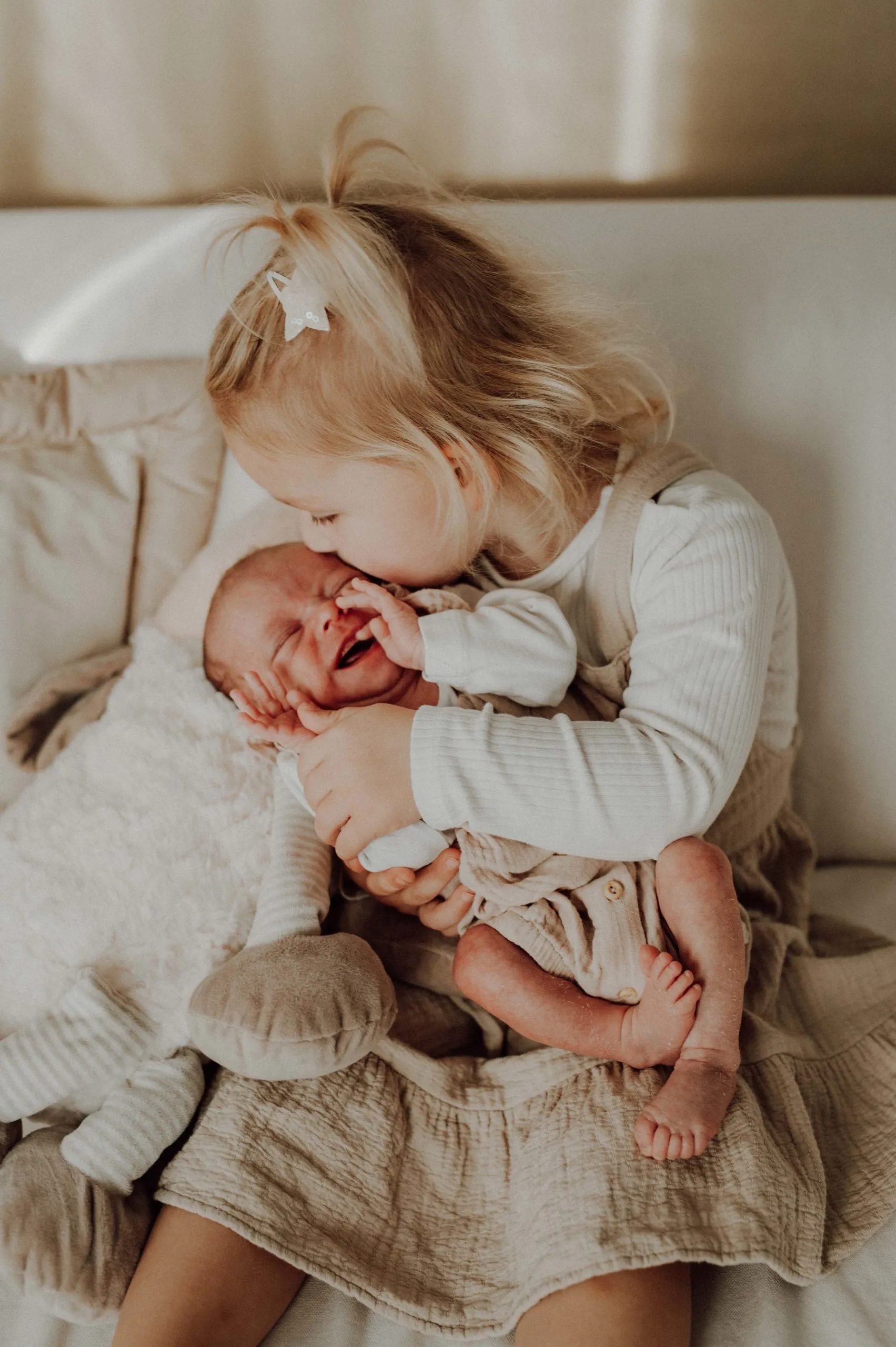Babyfotografie Babybauch Familienfotografie Pulheim Kleines Mädchen hält ein Baby auf dem Schoß und küsst es fotografiert von Valerija Ecker
